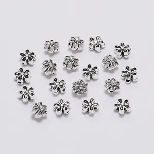 Macro view of flower-shaped alloy spacer beads with vintage silver finish for jewelry making