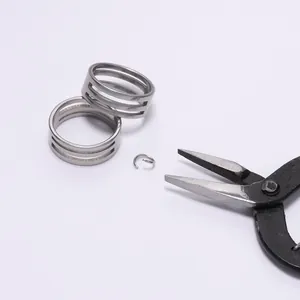 Detail view of stainless steel jump ring opener tool with silver metal rings and jewelry pliers
