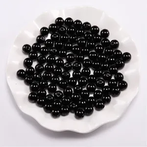 Macro view of glossy black ABS imitation round pearls with holes for DIY jewelry