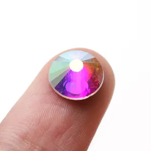Macro shot of Aurora AB crystal rhinestone with multiple facets on finger for DIY nail art