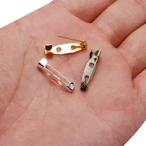 Bases d'épingles à broche en métal tricolores pour bijoux DIY montrées dans une paume
