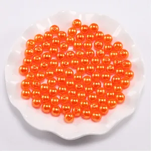 Close-up of vibrant orange ABS faux pearls with glossy finish for DIY jewelry crafts