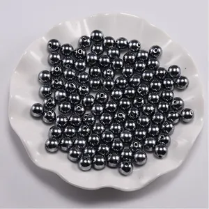 Macro shot of dark grey metallic ABS faux pearls with center holes in a white ceramic bowl