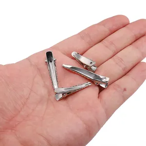 Assorted silver metal alligator hair clips in four sizes displayed on a hand palm