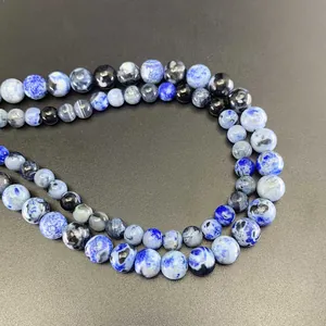 Macro shot of natural blue sodalite round beads showing unique mineral textures on black surface