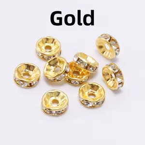Detailed view of ten gold-colored spacers with white rhinestones on a white background