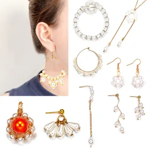 Detalle del set de joyería DIY con perlas, pendientes dorados y colgante naranja
