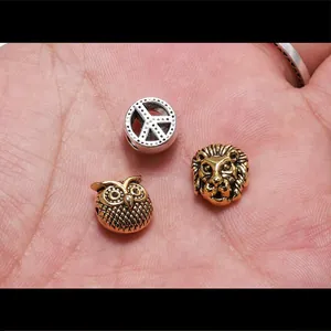 Macro shot of antique gold and silver beads featuring lion, owl and peace symbol charms
