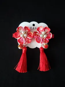 Detail of red handmade flower hairpins with silk tassels and golden bells on card