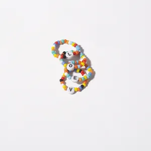 Détail macro de bagues en perles multicolores avec lettres LOVE sur fond blanc