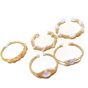 Detail of five handmade gold-plated wire-wrapped cuff bracelets with assorted white pearls