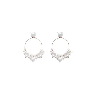 Detail of elegant gold hoop earrings featuring multiple radiant white pearls and polished finish