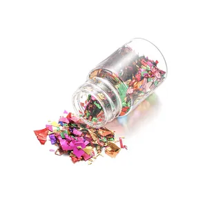 Macro shot of colorful iridescent candy paper flakes spilling from a small 15ml glass bottle