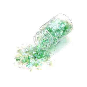 Irregular iridescent green glitter flakes spilling from a 15ml clear glass bottle