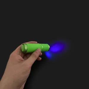 Handheld 12W UV LED nail lamp with green aluminum body showing blue light beam in use