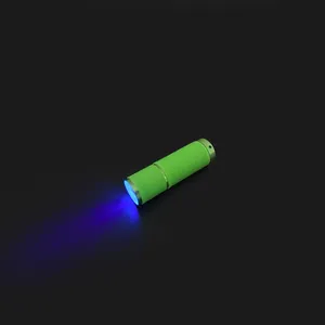 Detail of green mini LED nail lamp showing non-slip texture and purple UV light beam