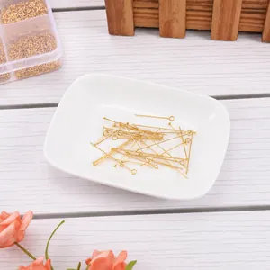 Goldene Edelstahlnadeln und T-Stifte für DIY-Schmuckherstellung in einer Schale