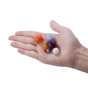 Colorful round chalcedony style beads in various sizes held in hand for DIY jewelry making