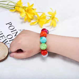 Detail of colorful marble-textured round beads worn on wrist with floral background