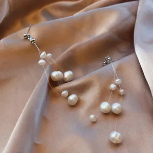 Boucles d'oreilles longues à franges en perles d'eau douce blanches sur satin champagne