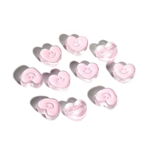 Macro shot of pink heart-shaped acrylic beads with smiley face for DIY jewelry crafting