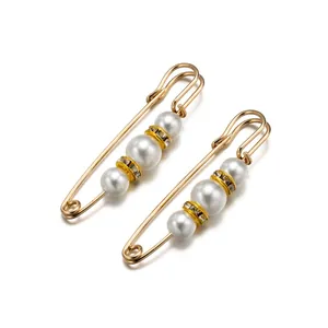 Detalle de imperdibles dorados con perlas blancas y anillos de cristal resplandecientes