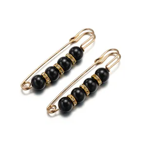Primer plano de dos elegantes broches de imperdible dorados con perlas negras y cristales