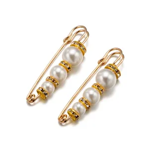 Detalle macro de broches de imperdible dorados con perlas blancas y diamantes de imitación