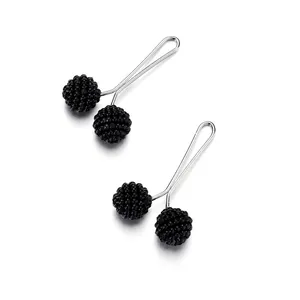 Close-up of black beaded U-shaped hijab pins with detailed textured finish on metal
