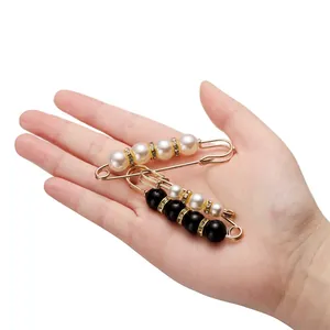 Elegante broche de imperdible dorado con perlas artificiales blancas y negras y pedrería