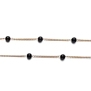 Close-up of gold chain with black spherical beads for DIY jewelry making