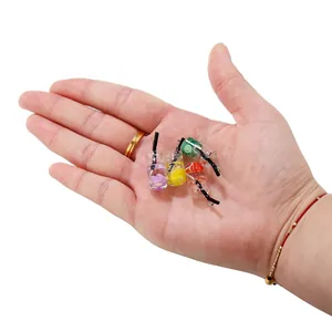 Gros plan de pendentifs miniatures en résine de bouteilles de fruits dans une main