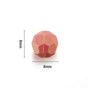 Vue macro d'une perle acrylique facettée rouge de 8mm avec paillettes dorées pour bijoux