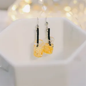 Détail de boucles d'oreilles bouteille en verre avec tranches d'orange et paille