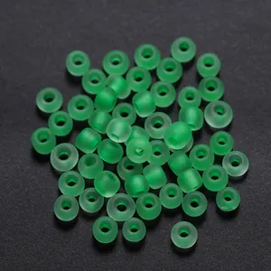 Detalle macro de cuentas de vidrio verde mate de 3 mm con orificio central para joyas DIY