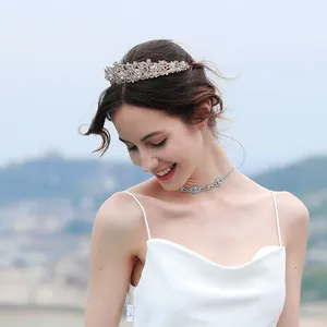 Detalle de corona de novia con cristales y collar a juego en modelo con vestido blanco