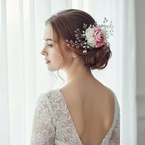 Detail of bridal hair comb with pink artificial flowers, pearls, and crystal beads on a model
