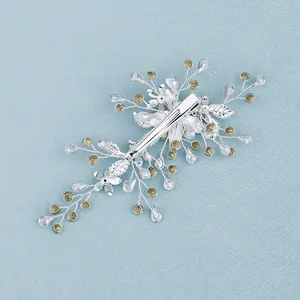 Handmade floral hair clip with silver vine design and crystal beads on a blue background