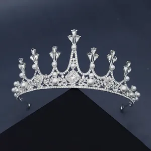 Detail der silbernen Brautkrone mit schimmernden Strasssteinen und weißen Perlen auf dunklem Grund