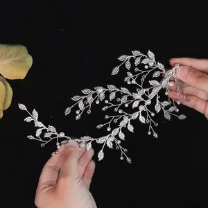 Accesorio de pelo nupcial plateado con perlas blancas y diseño de hojas en manos