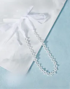 Détail de collier en perles tissées et rubans d'organza sur une surface en marbre