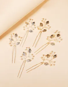 Detailed view of handcrafted gold and silver U-shaped hair pins with pearls and leaf accents
