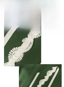 Close-up of bridal lace headband with hand-sewn beads and crystals on dark green velvet