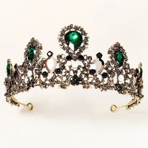 Detailed macro of Baroque gold crown with emerald green teardrop gems and crystals