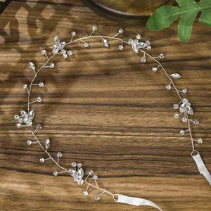 Macro view of handmade bridal hairband with crystal leaf details and white ribbons