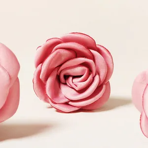 Close-up of pink satin rose hair pin with layered fabric petals for bridal hair styling