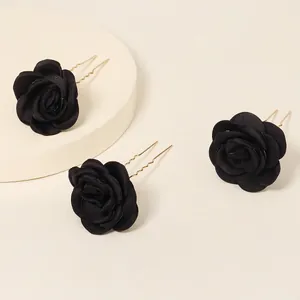 Detailed view of three black satin rose bridal hair pins with gold-tone U-shaped metal stems