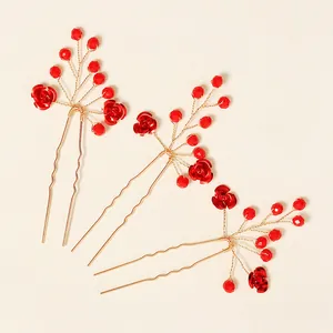 Détail de trois épingles à cheveux de mariée avec perles rouges et fils dorés tressés