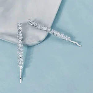 Close-up of two silver-plated hairpins with rectangular zircon stones on marble background