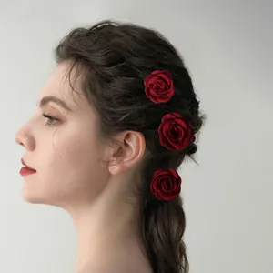 Three deep red velvet rose hair pins on model's hair for bridal hair styling